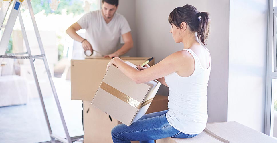 Женщина ищет коробки на столе. Men make Houses women make Homes. Organize your belongings for moving. When you are preparing